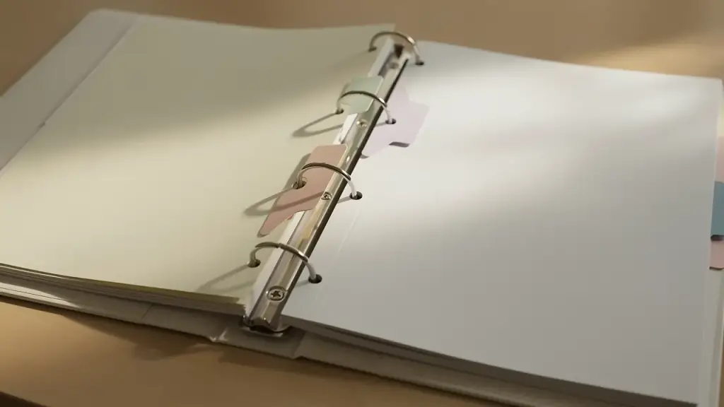 An open ring binder on a desk with its coloured tab dividers fanned across the page
